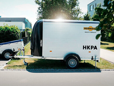 HKPA Seitenansicht | © Humbaur GmbH Seitenansicht des Kofferanhängers HKPA abgestellt auf einer Grünfläche in einem Wohngebiet | © Humbaur GmbH