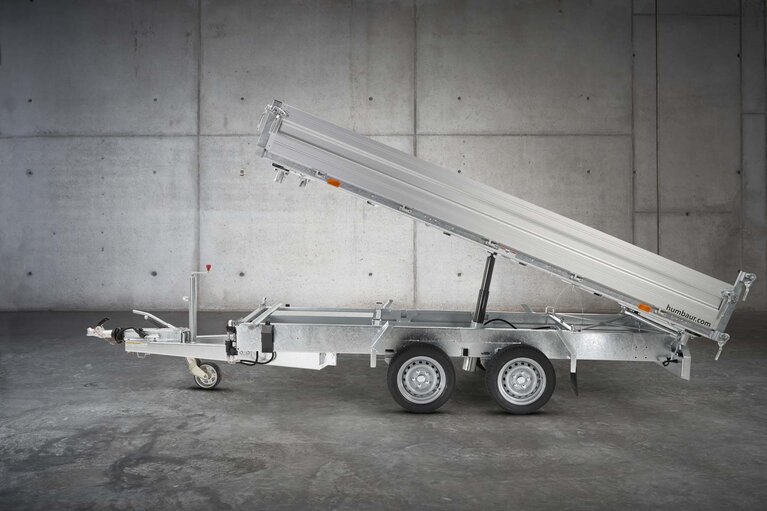 Un camion à benne basculante à deux essieux de couleur argentée