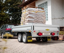 Beladener Humbaur Anhänger mit Baumaterial wird von Auto gezogen | © Humbaur GmbH